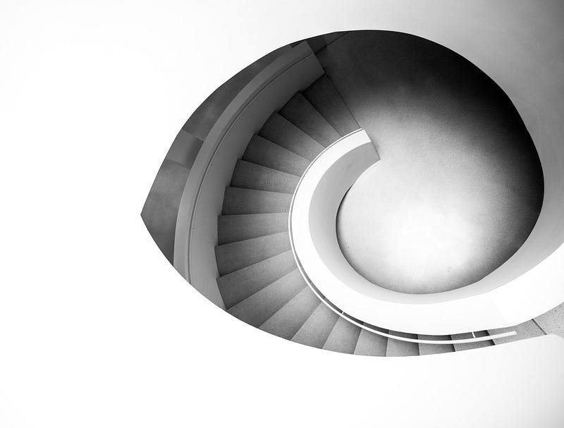 Image of a white stairwell winding downwards.